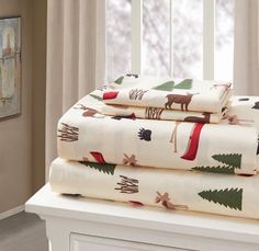 three sheet sets with christmas trees and deers on them in front of a window