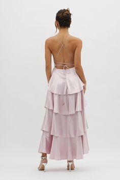 the back of a woman wearing a pink dress with ruffles and straps on it