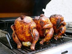 three chickens are cooking on the grill outside