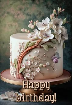 a birthday cake with flowers on it and the words happy birthday written in gold lettering