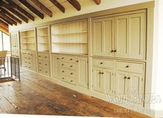 an empty room with wooden floors and white cabinets