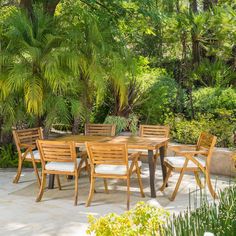 a wooden table and chairs sitting on top of a stone patio surrounded by palm trees