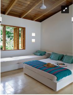 a bed room with a neatly made bed next to a window and two white couches