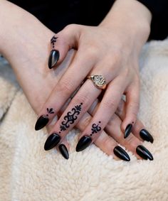 a woman's hands with black nail polish and tattoos