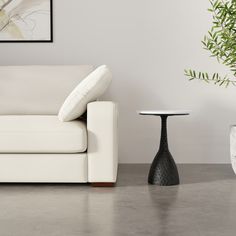 a white couch sitting next to a table with a vase on it's side