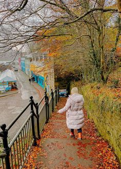 a woman walking down a path in the fall