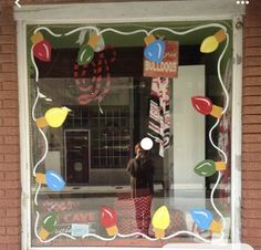 a person taking a photo in the window of a store with balloons and candy canes