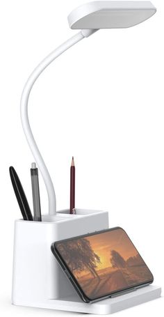 an electronic device with a pen, pencil and phone in it sitting on a stand