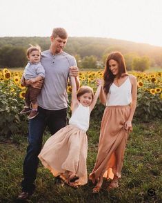 a man, woman and child are holding hands in front of a sunflower field