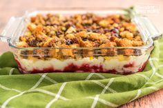 a casserole dish filled with fruit and crumbled toppings on a green cloth