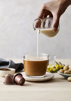 someone pours coffee into a glass cup on a plate with other ingredients around it