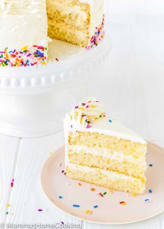 a slice of cake with white frosting and sprinkles on a plate