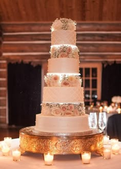 a three tiered wedding cake sitting on top of a table next to lit candles