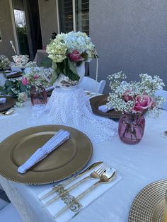 the table is set with gold and white plates, silverware, and flowers in vases