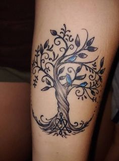 a tree tattoo on the arm with blue leaves