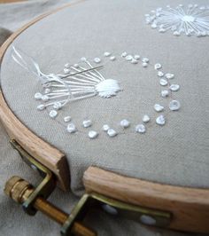 a close up of a embroidery on a pillow with buttons and needles in it's center