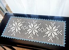 a black table with a white doily on top of it and a wooden floor in the background