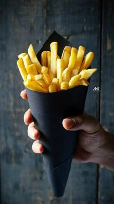 a hand holding a cone of french fries