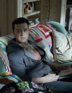 a man sitting on top of a couch next to pillows