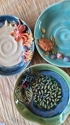 three plates with sea creatures on them sitting on top of a wooden table next to each other