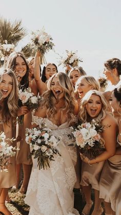 a group of women standing next to each other holding bouquets in their hands and laughing