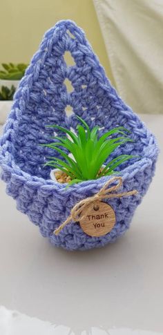 a blue crocheted basket with a plant in it and a thank you tag