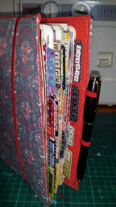 a red case holding magazines and pens on a green cutting board