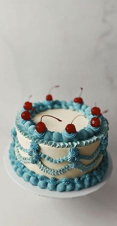 a blue and white cake with cherries on top