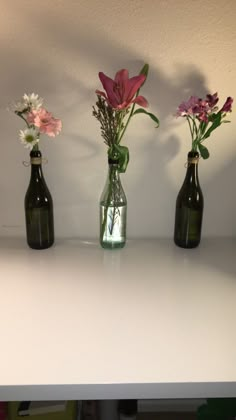 three bottles with flowers in them sitting on a table