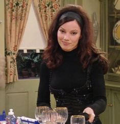 a woman standing in front of a table filled with wine glasses