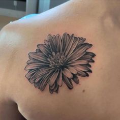 a black and white flower tattoo on the back of a woman's shoulder