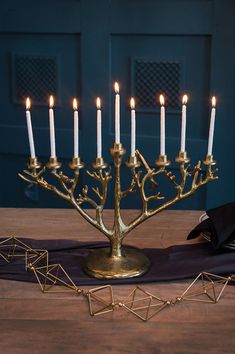 a golden menorah with lit candles sits on a table