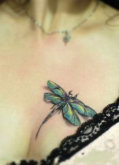 a close up of a woman's chest with a dragonfly tattoo on it