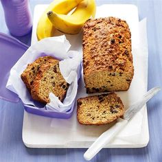 a loaf of banana bread sitting on top of a cutting board next to some bananas