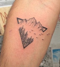 a man's arm with a mountain and birds tattoo on it