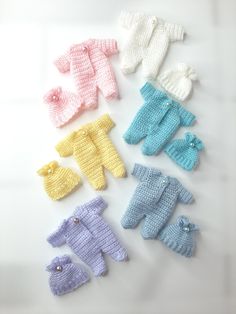 several knitted baby clothes are arranged on a white surface, one is blue and the other is yellow