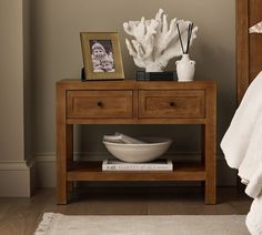 a white bowl sitting on top of a wooden table next to a vase with flowers