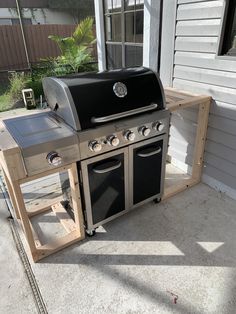 an outdoor bbq with two grills on the side of it and a table next to it