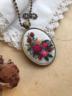 a close up of a necklace on a table near a piece of cloth and flowers