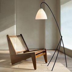 a wooden chair sitting next to a lamp on top of a hard wood floor