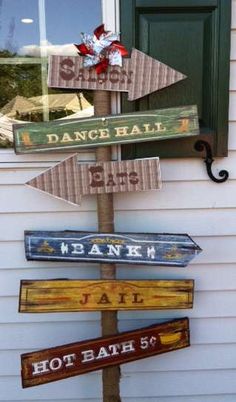 a pole with many different signs on it in front of a building that says dance hall and hot bath