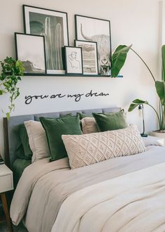 a bed with green pillows and pictures on the wall above it, in a bedroom