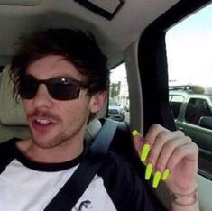 a man with yellow nails sitting in the back seat of a car and pointing at something