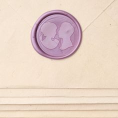 a purple wax seal with the image of two people kissing