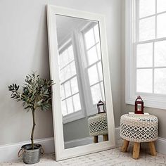 a mirror sitting on top of a table next to a small stool and potted plant