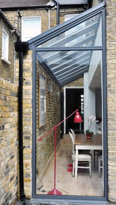 the reflection of a table and chairs is seen in an open door to a brick building