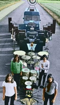 three people standing in front of a truck with musical equipment on the road next to it