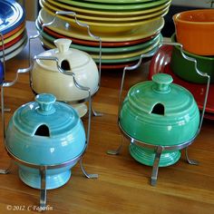 many different colored dishes are stacked on top of each other in front of a stack of plates