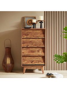 a wooden chest of drawers sitting next to a vase with candles on top of it