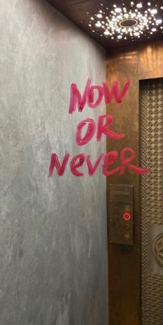 graffiti on the side of a wall next to a door with words now or never written on it